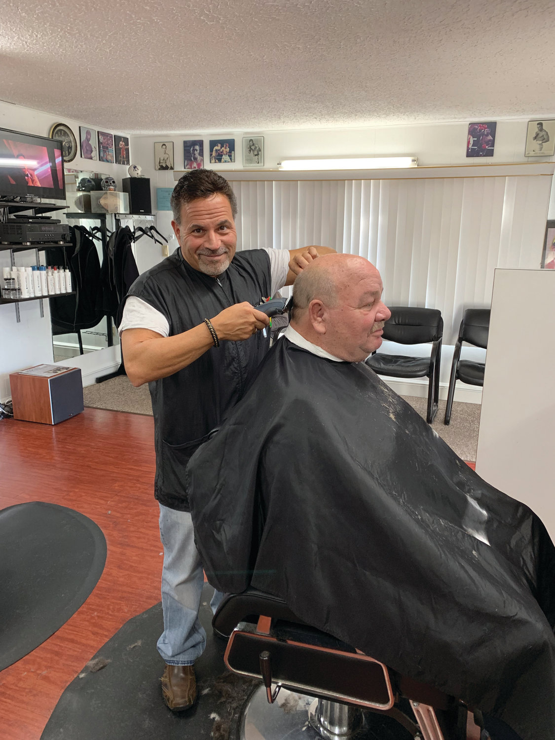 Dave Picozzi catches the lens of the camera as he cuts the hair of longtime customer Roy Kelvey.  Roy and Dave have known each other for over 30 years when Dave first started cutting Roy’s hair. Loyalty and longevity are two things David’s Greenwood Barbershop values and has worked hard for.